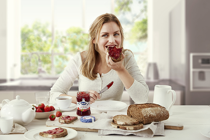 Woman eating a sandwich with jam.